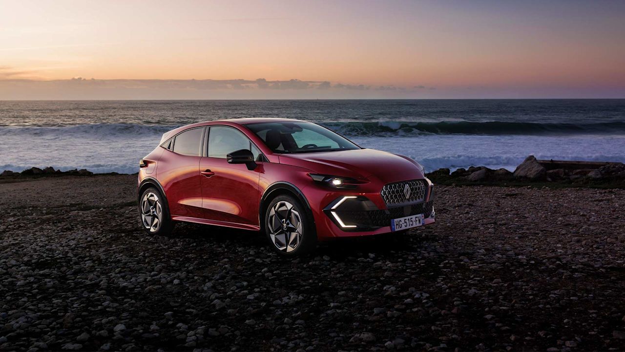 En-röd-sjätte-version-av-Renault-Clio-står-parkerad-framför-havet-under-solnedgång